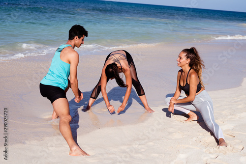 Cuadro en lienzo Three young people limbering up on the waters edge