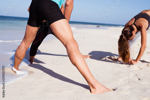 Two girls and a boy exercising on the beach