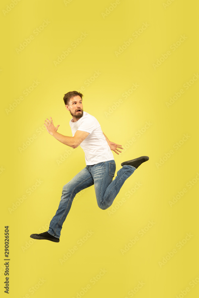Full length portrait of happy jumping man isolated on yellow background. Caucasian male model in casual clothes. Freedom of choices, inspiration, human emotions concept. Run for sales, hurry up. Full length portrait of happy jumping man isolated on yellow background. Caucasian male model in casual clothes. Freedom of choices, inspiration, human emotions concept. Run for sales, hurry up.