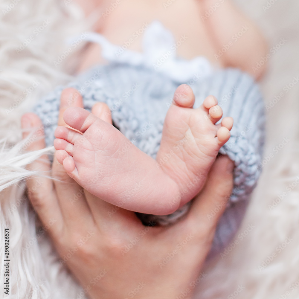 Parents holding in the hands little feet of newborn baby closeup Parents holding in the hands little feet of newborn baby closeup