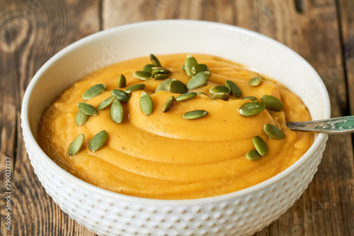 Thick pumpkin cream soup with seeds in a white bowl 
