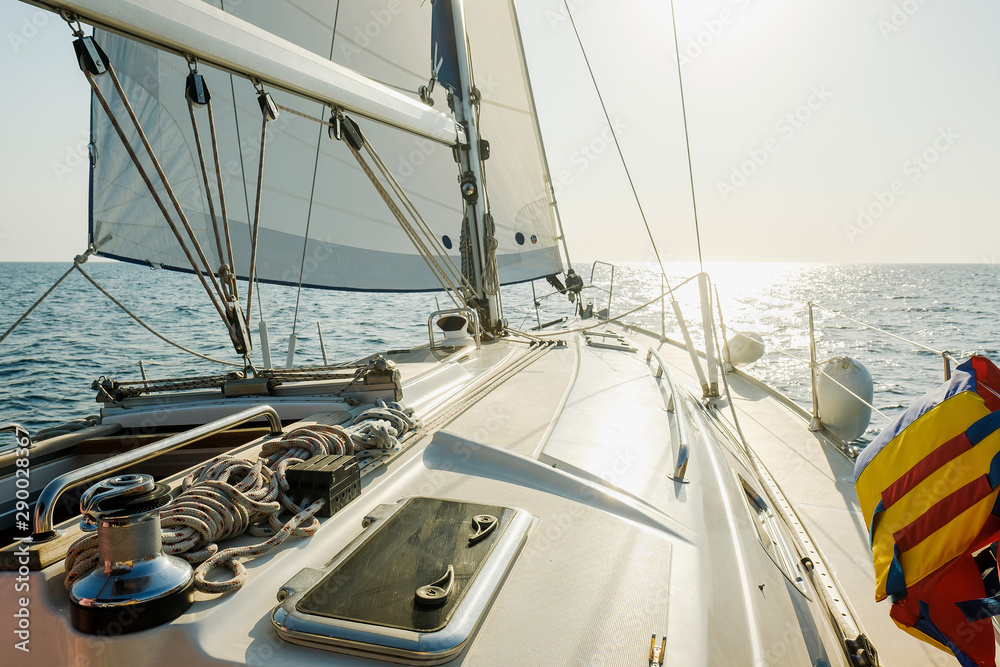 Yacht on ocean. Sailing ship with white sails in the open sea. View from the yacht's deck to mast and sail. Sport, vacation, travel, summer, activity concept