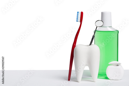 Dental health and teethcare concept. Dental mirror in white tooth model near mouthwash, toothbrush and dental floss against white isolated background.