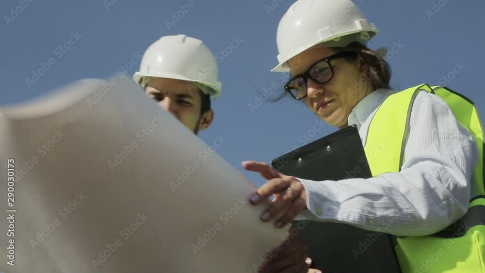 Two Young Engineers A Man And A Woman In Green Vests And Helmets