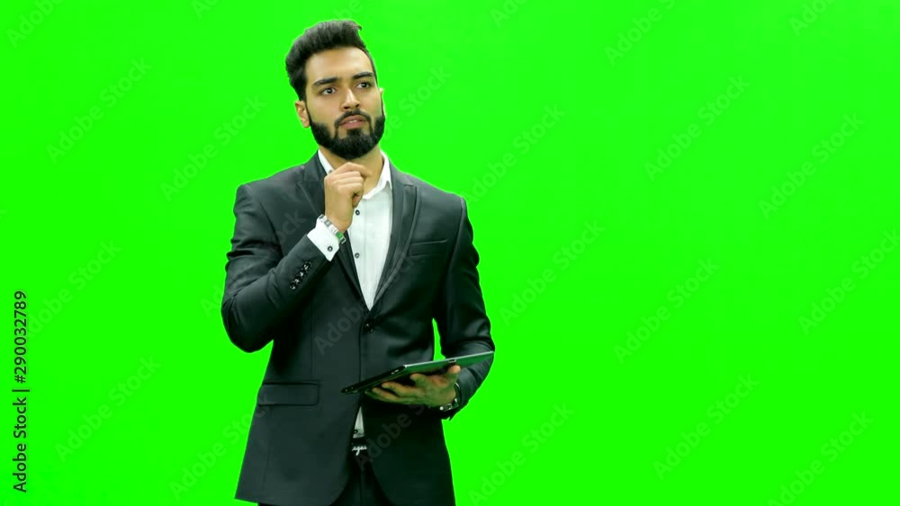 Young man dressed formally using tablet and making hand movements on virtual green screen. 