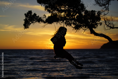girl on a swing at sunset