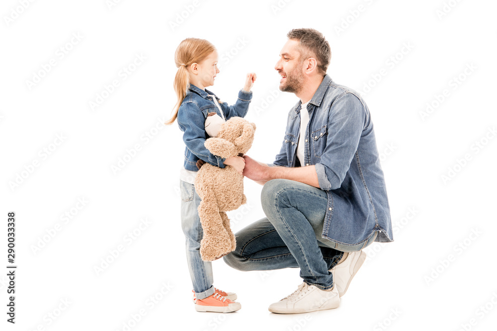 side view of daughter with teddy bear and bearded dad looking at each other isolated on white side view of daughter with teddy bear and bearded dad looking at each other isolated on white