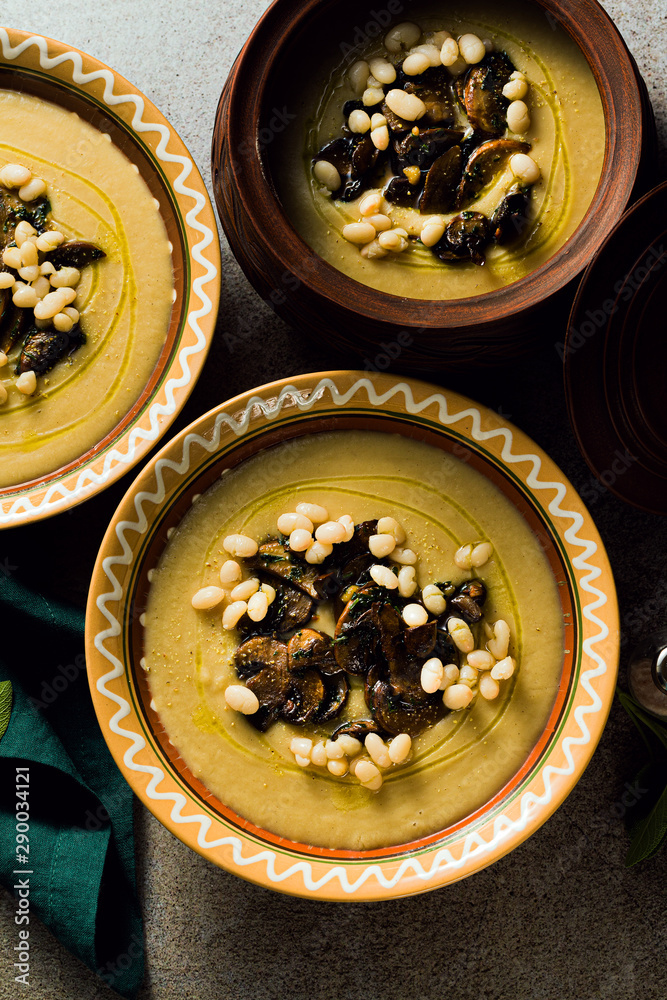 mushroom soup with Italian cannellini beans and fennel in clay pots on a table. Autumn healthy vegan food. top shot
