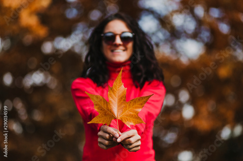young woman outdoors in a park holding a brown leave. Autumn concept. Selective focus © Eva