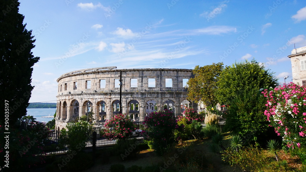 Pula, Kroatien: Blick aufs Amphitheater hinter bunten Pflanzen