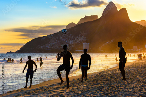 Brazilian boys play football on Ipanema beach at sunset in Rio de Janeiro, Brazil.