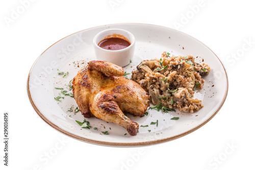 Half chicken tobacco with cooked buckwheat with mushroom and tomato sauce isolated on white background