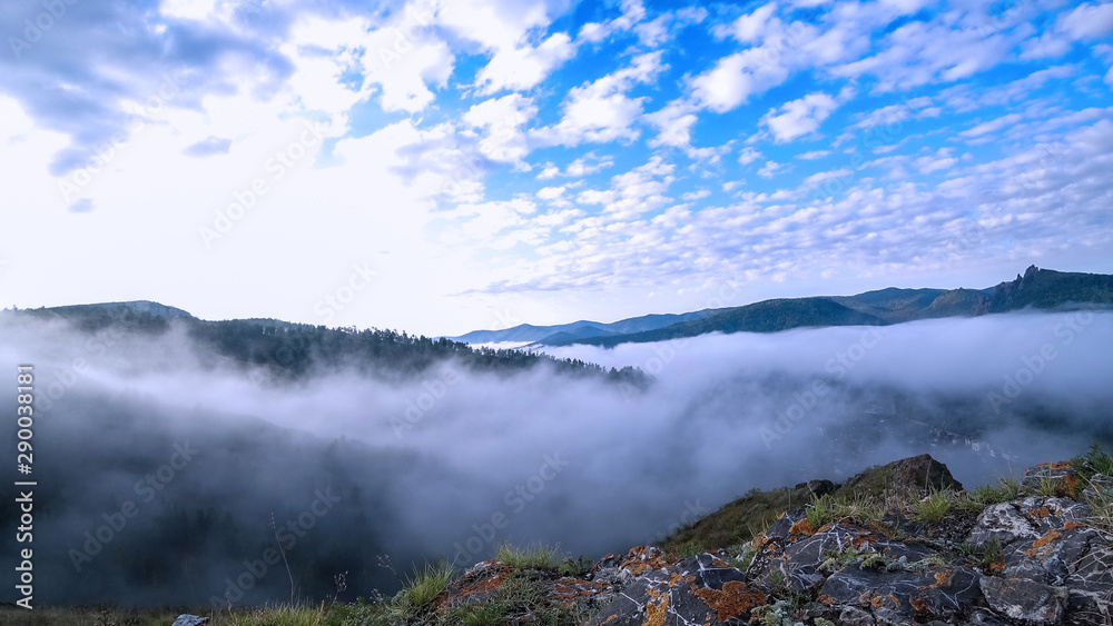 Bright sunlight illuminates the mountain and dense fog moving through the gorge. Clouds are moving. Bright sunlight illuminates the mountain and dense fog moving through the gorge. Clouds are moving.