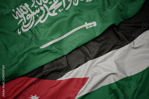 waving colorful flag of jordan and national flag of saudi arabia.