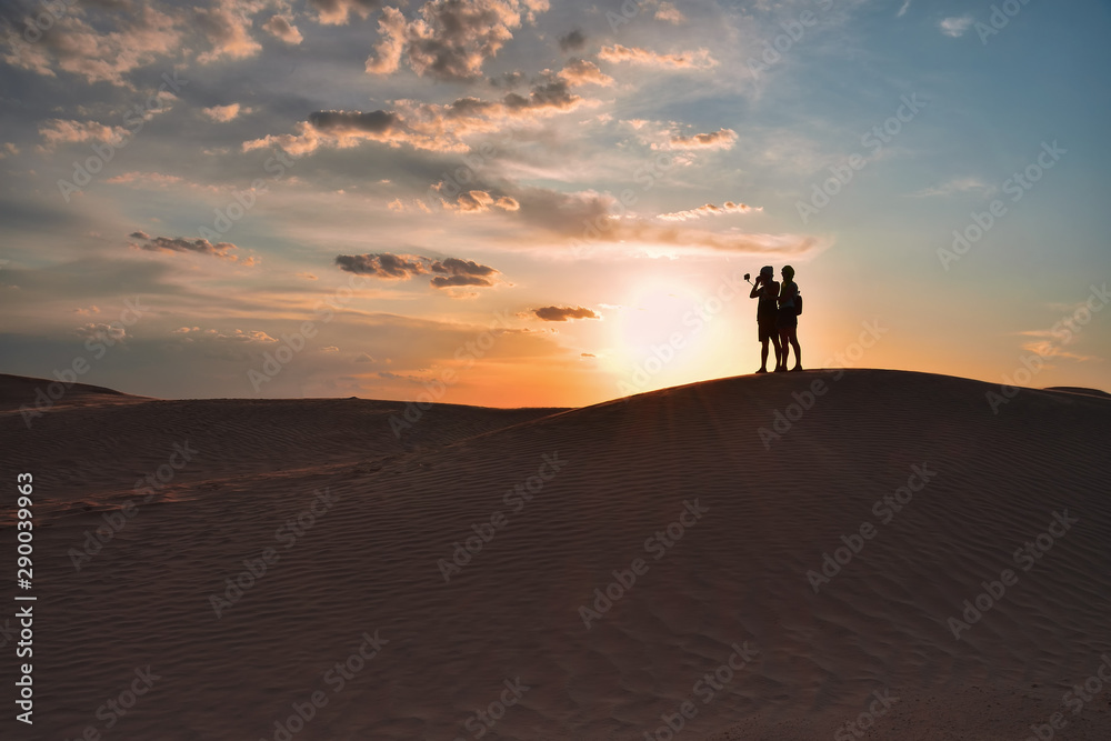 silhouettes of a man and a woman on top of a sand dune in the Sahara desert