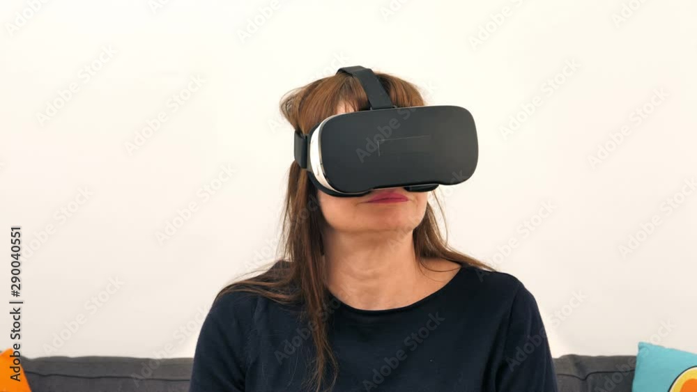 A mature woman wears virtual reality glasses and looks around.
