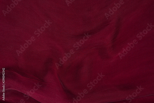 Soft smooth burgundy silk fabric background. Fabric texture.