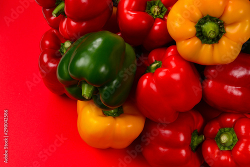 Fresh red, yelow, green bell pepper on a red background.