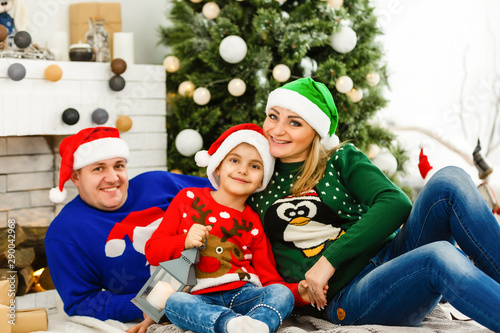 The charming family sitting near Christmas Tree