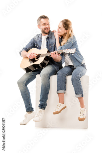 smiling man in jeans playing acoustic guitar for wife isolated on white
