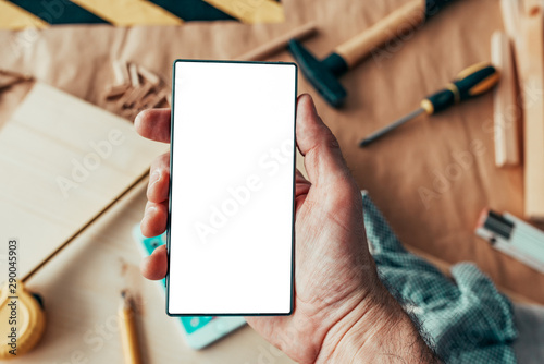 Handyman maintenance worker holding smartphone with blank mock up screen