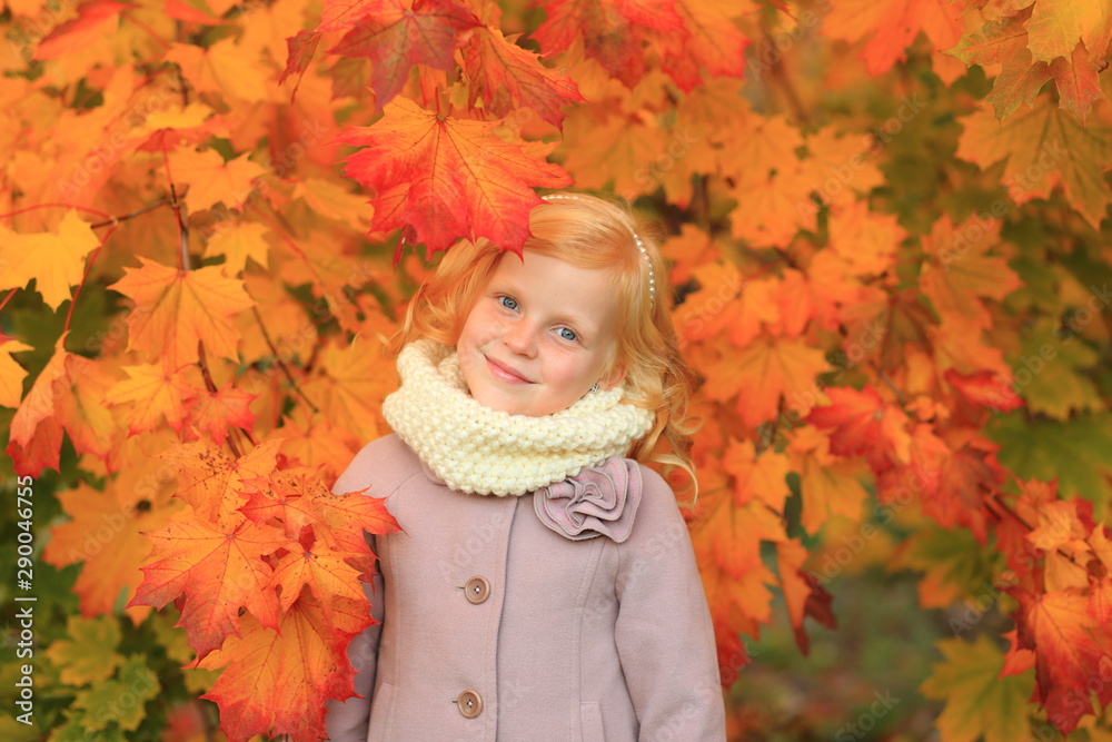 A girl with red hair plays in the autumn park. Autumn palette. Portrait of ginger child A girl with red hair plays in the autumn park. Autumn palette. Portrait of ginger child