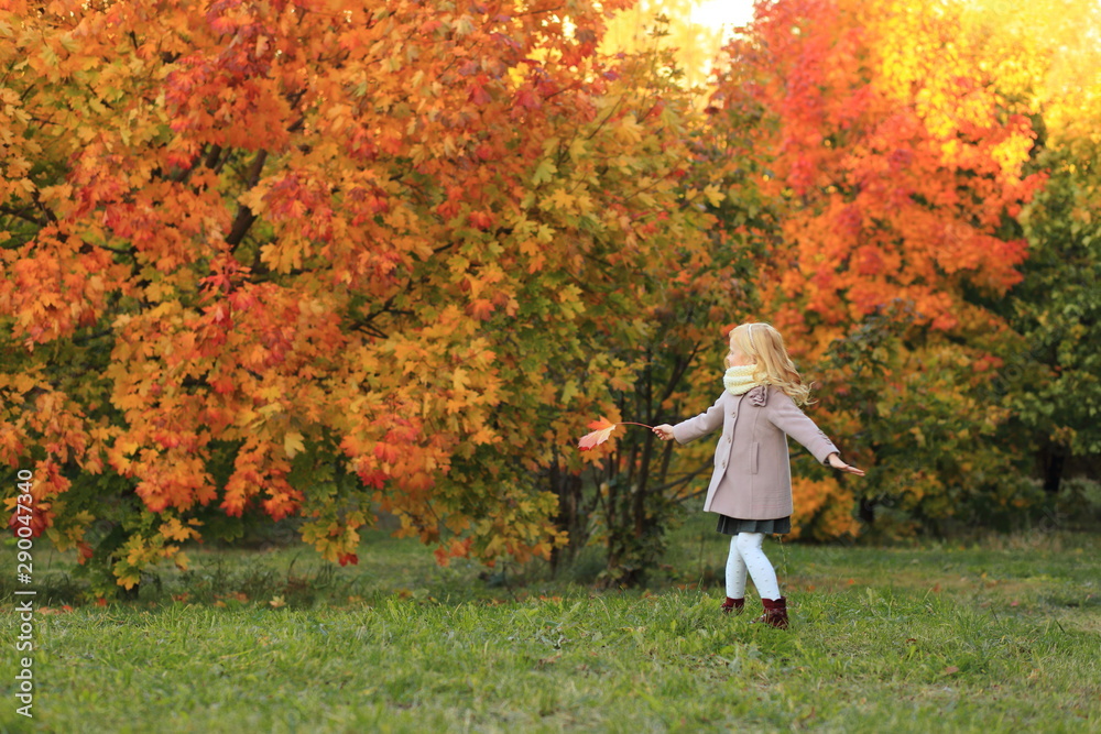 A girl with red hair plays in the autumn park. Autumn palette. Portrait of ginger child A girl with red hair plays in the autumn park. Autumn palette. Portrait of ginger child