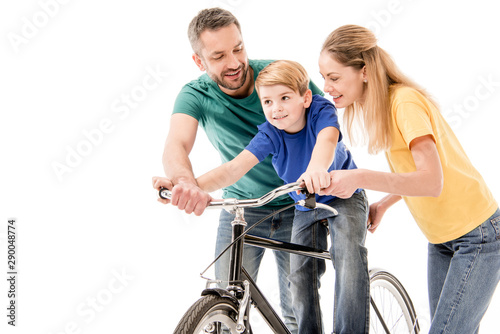 smiling parents teaching son to ride bike isolated on white