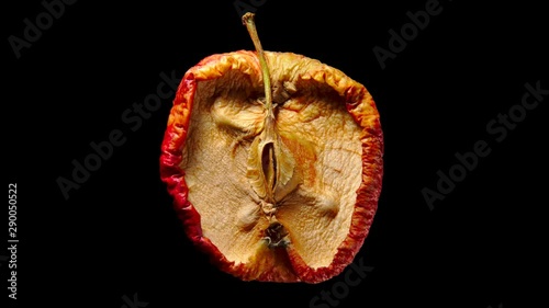 Half of fresh ripe yellow apple drying process. Time lapse shot, isolated on black background. Fruit quickly become small and wrinkled