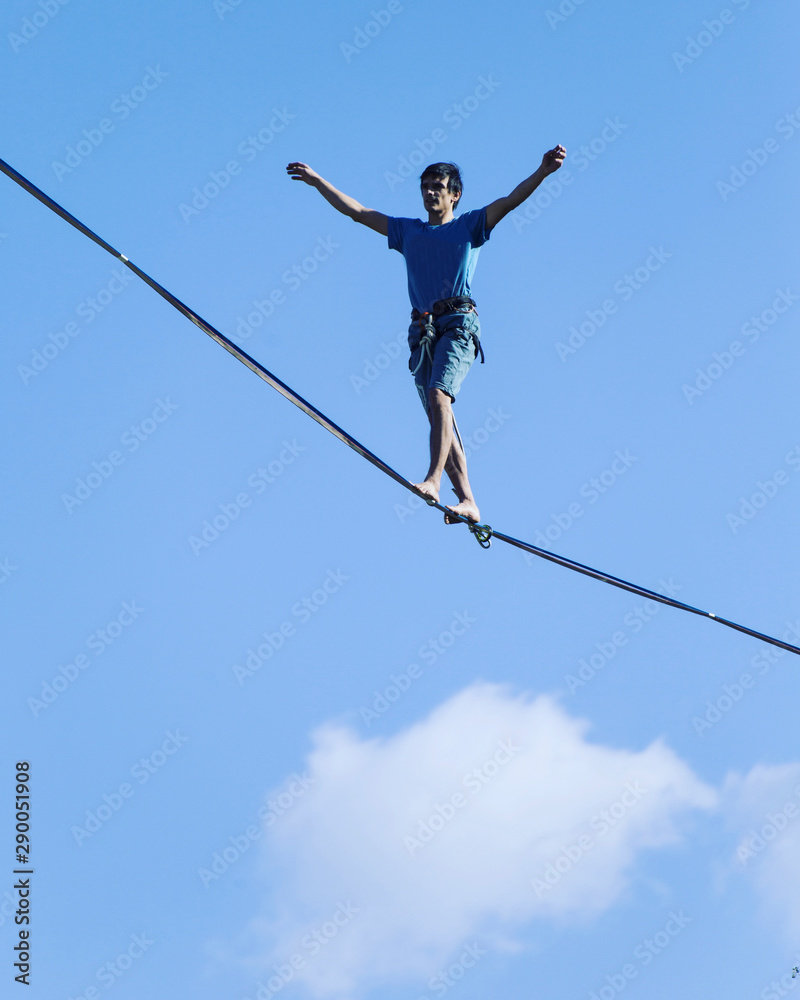 A man is walking along a stretched sling. Highline in the