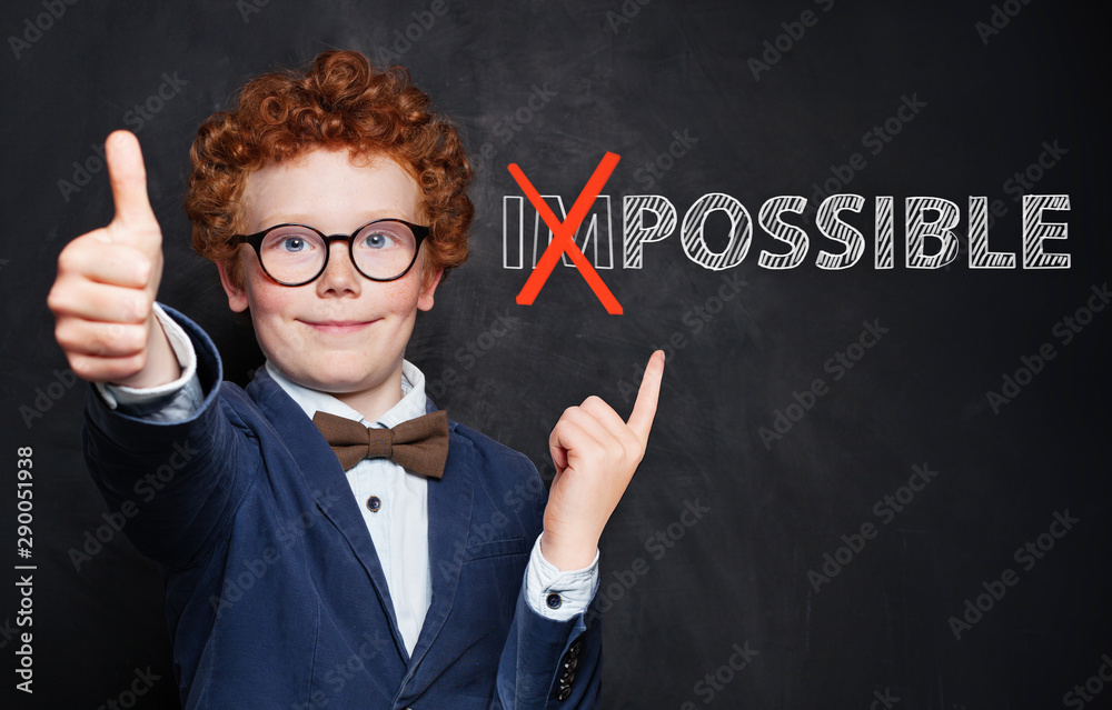 Happy smart child pointing at possible inscription on chalkboard background. Success and develop concept - obrazy, fototapety, plakaty 