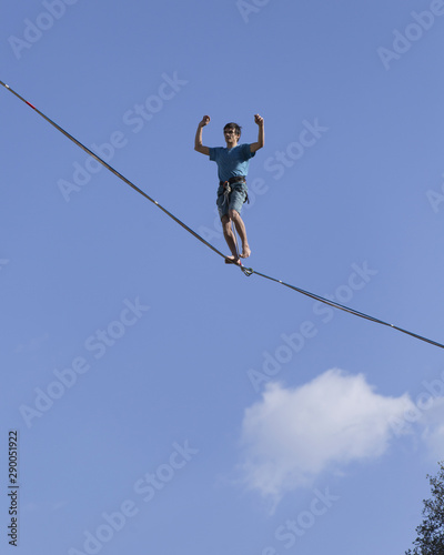 A man is walking along a stretched sling. Highline in the mountains. Man catches balance. Performance of a tightrope walker in nature. Highliner on the background of the mountains.