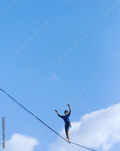 A man is walking along a stretched sling. Highline in the mountains. Man catches balance. Performance of a tightrope walker in nature. Highliner on the background of the mountains.