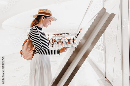 Asian girl uses touchscreen terminal to find the right boutique in a big shopping Mall photo