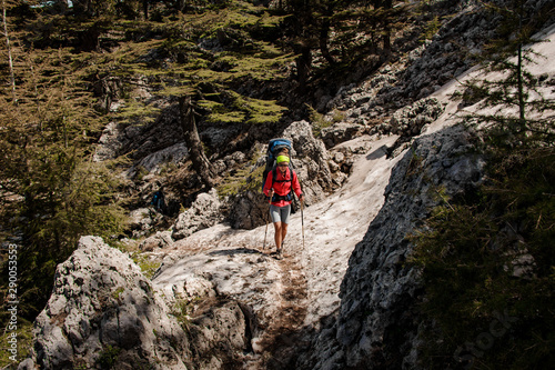 Girl walking up on the Tahtali mountain with hiking backpack and sticks