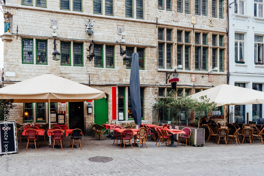 Old narrow street with tables of cafe in Ghent (Gent), Belgium. Architecture and landmark of Ghent. Cozy cityscape of Ghent.