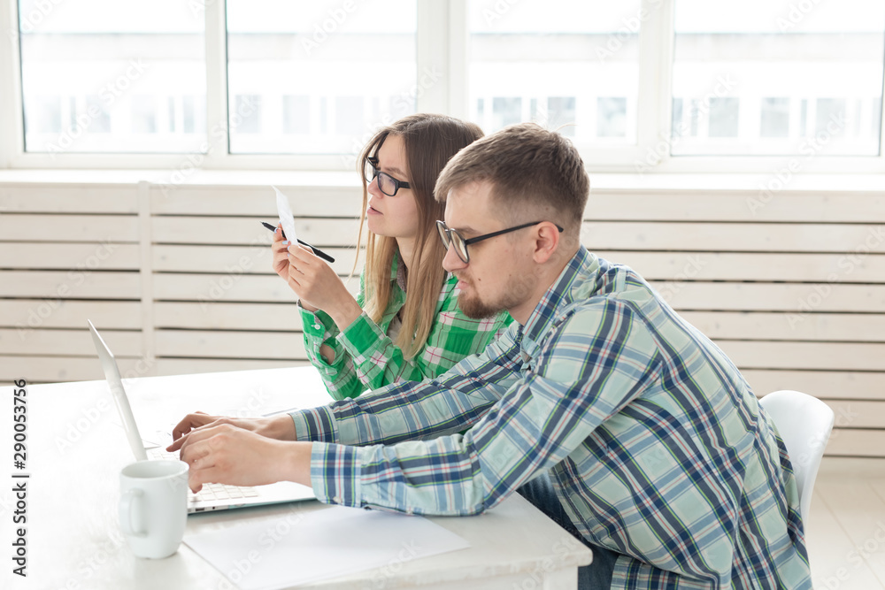 Dissatisfied young husband and wife recount utility bills for payment of an apartment and write the results in a notebook and laptop in their home accounting.