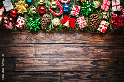 Christmas background with fir tree and decoration on dark wooden board, top view