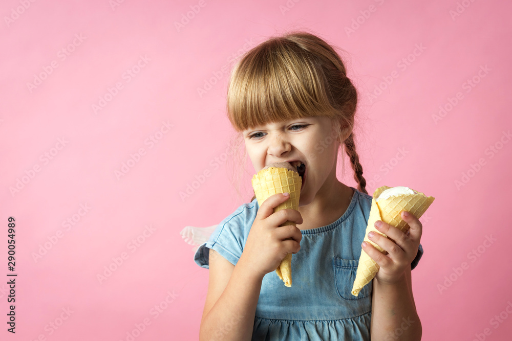 little girl with pigtails in a blue dress eating ice cream in a cone on a pink background little girl with pigtails in a blue dress eating ice cream in a cone on a pink background