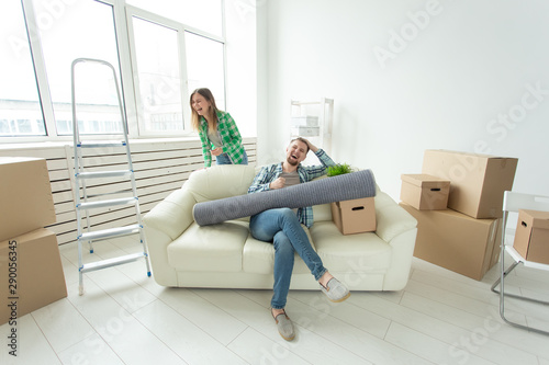 Positive crazy cheerful couple rejoices in moving their new apartment sitting in the living room with their belongings. Concept of housewarming and mortgages for a young family. © satura_