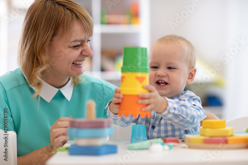 Baby with teacher playing with educational cup toys in day care