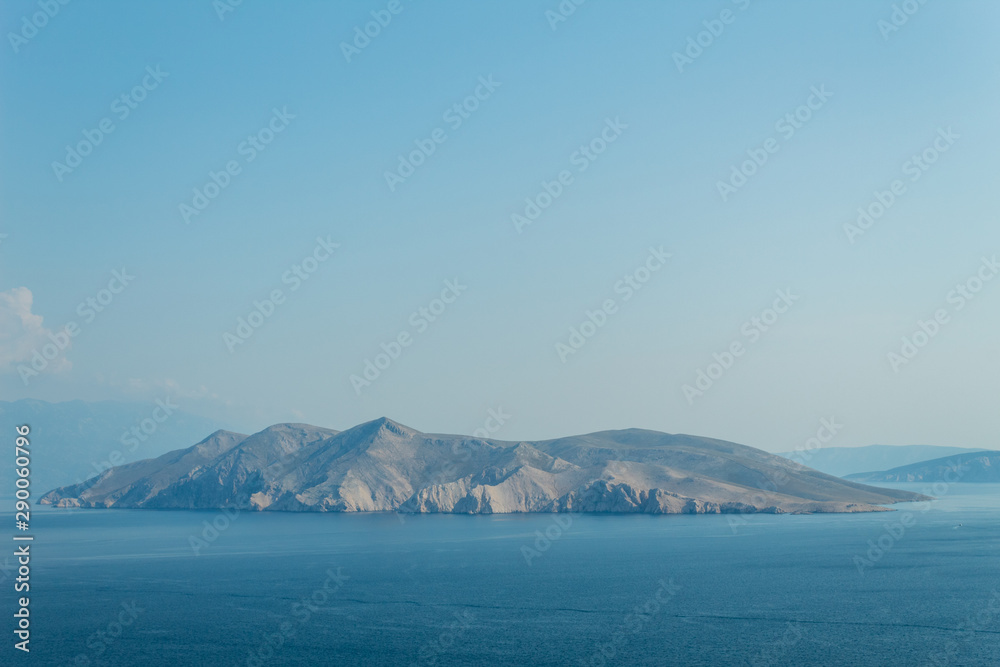 Seascape: rocky island, turquoise water, bright blue sky. Natural natural gradient of blue tones. Baska, island of Krk, Croatia.