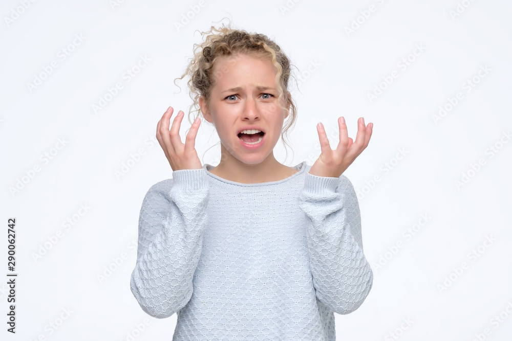 Pretty young blonde girl feeling angry and irritated. Studio shot. Negative facial human emotion Pretty young blonde girl feeling angry and irritated. Studio shot. Negative facial human emotion