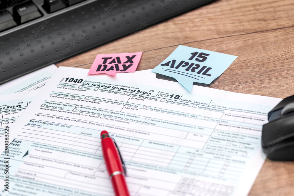 Fototapeta premium Tax form with pen, calculator, mouse, keyboard on wooden background