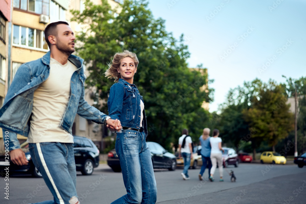 Young happy couple running crosswalk in the street