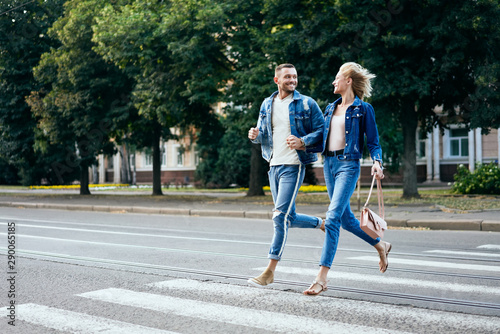 Young happy couple running crosswalk in the street