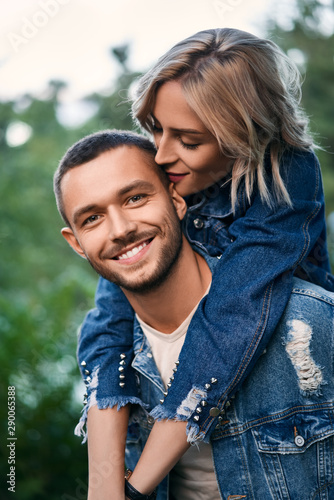 Young beautiful lovers have fun on nature. Smiling girl piggyback of her boyfriend