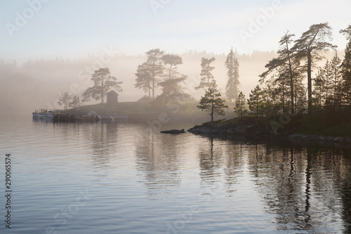 Morning misty landscape with silhouettes of trees, Valaam, Karelia, Russia.