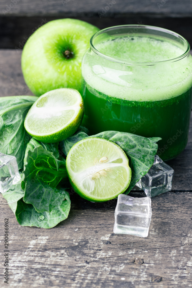 Fototapeta premium Green apple smoothie in glass and kale leaves on wooden table