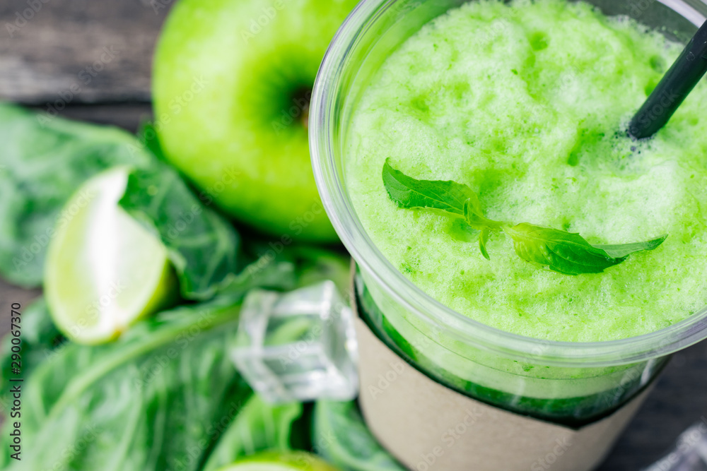 Green apple smoothie in glass and kale leaves on wooden table Green apple smoothie in glass and kale leaves on wooden table